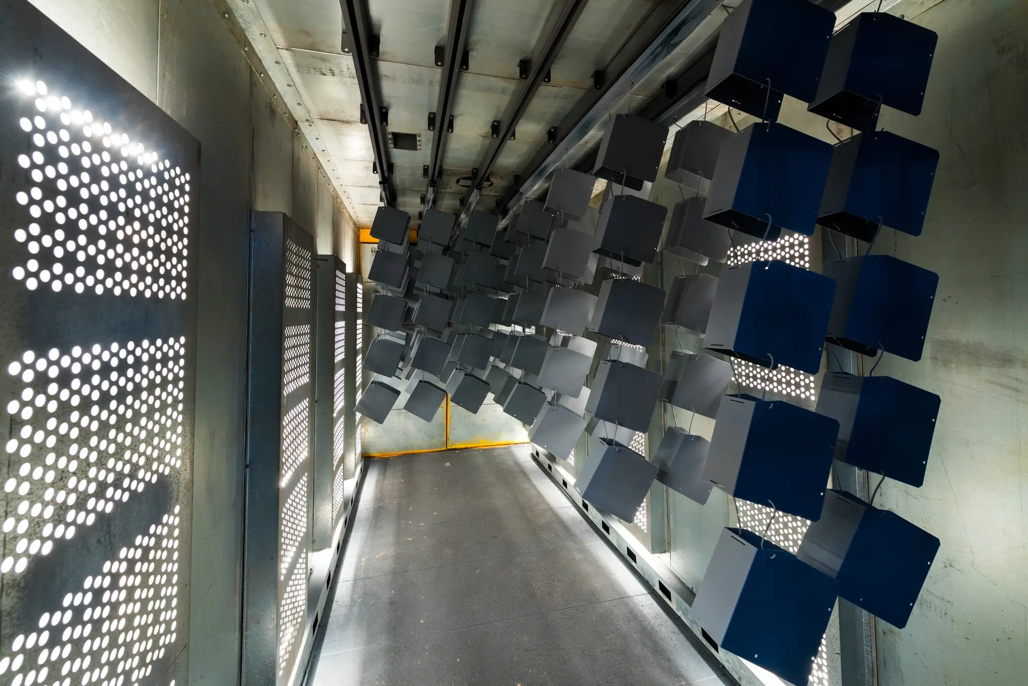 Automated powder coating line with metal housings moving into the curing oven.