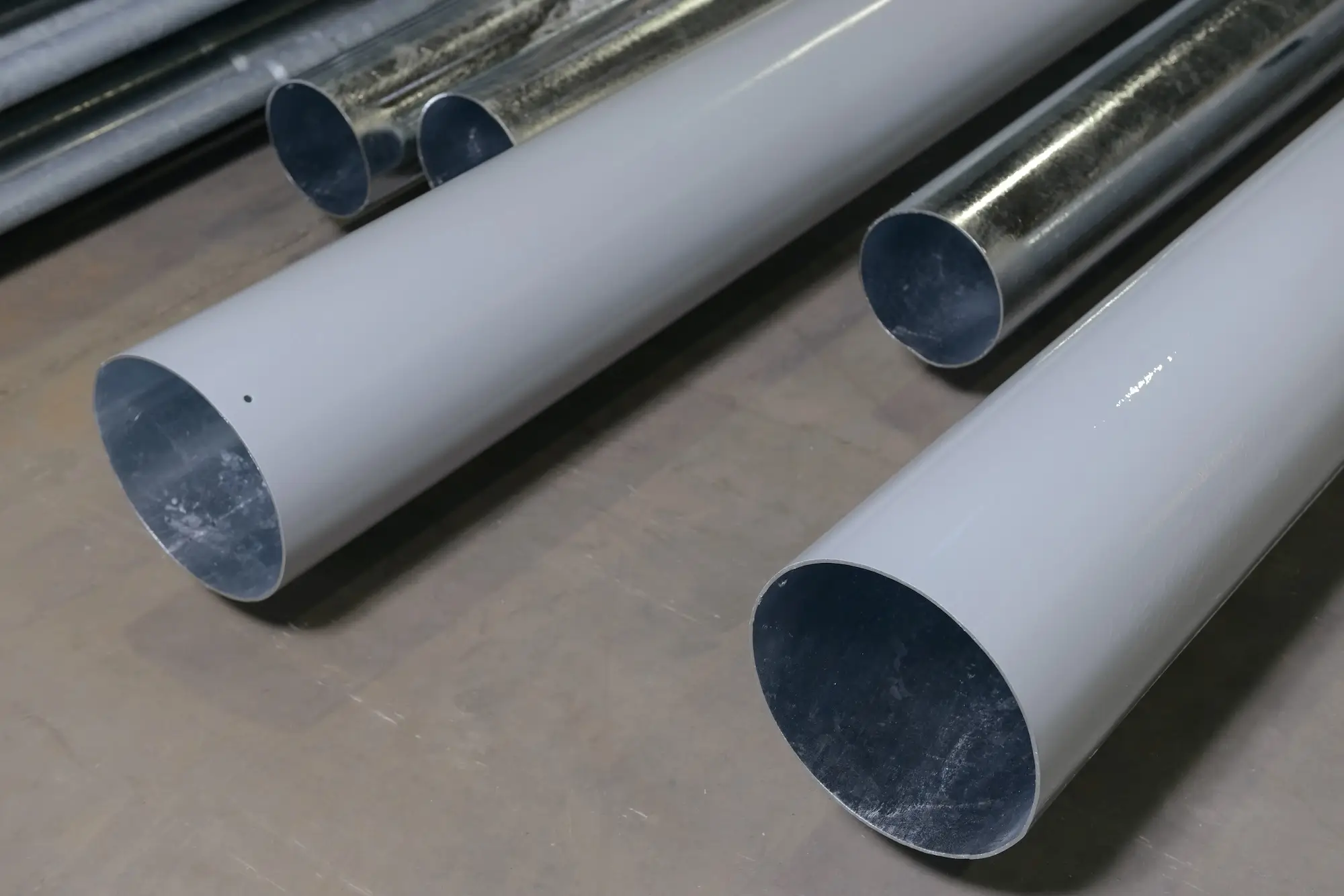 Comparison between hot-dip galvanized and Duplex system painted steel pipes in the factory warehouse.