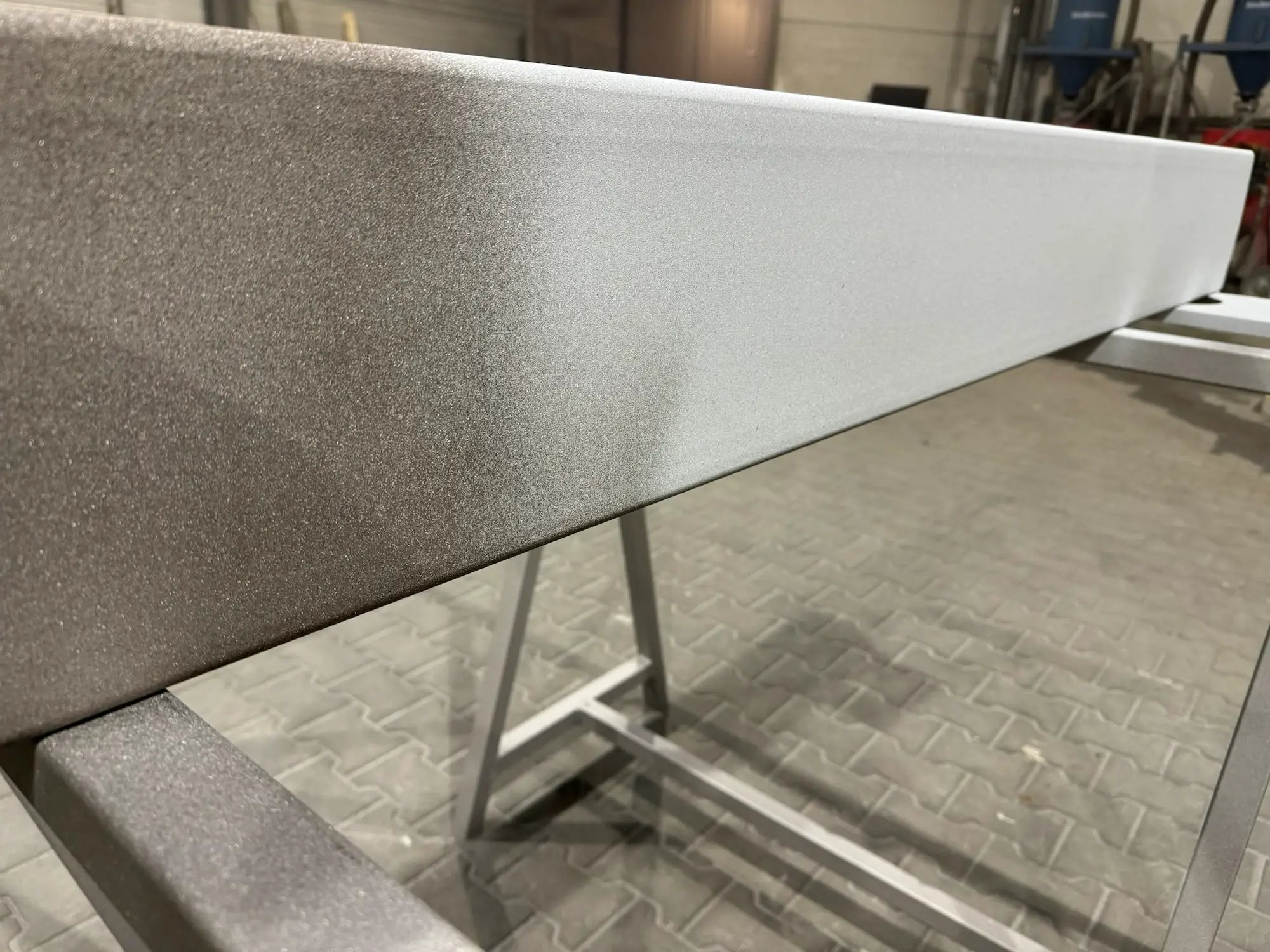 Close-up of the rough and matte texture of thermally sprayed zinc coating on a steel beam.
