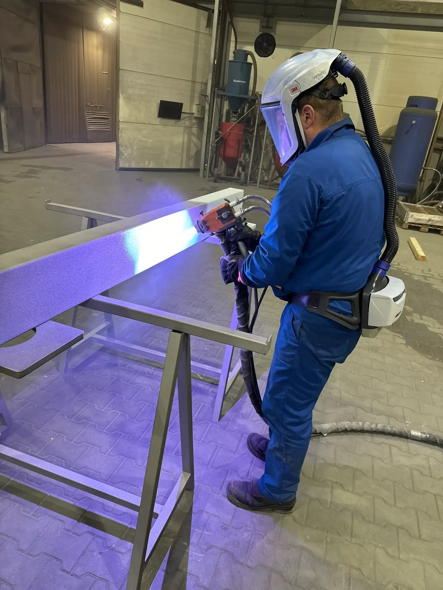Specialist performing thermal metallization of a steel beam using electric arc equipment.