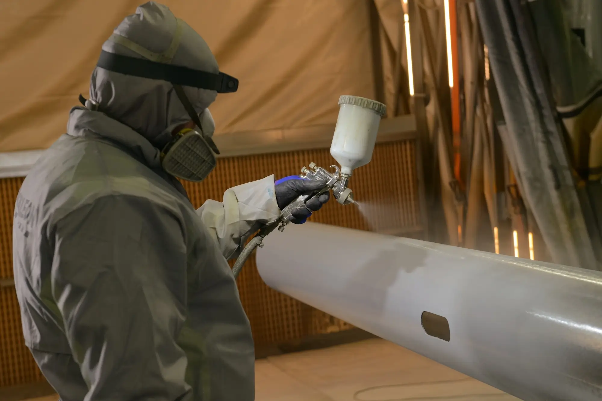 Painting metal structures with a high-pressure spray gun, ensuring a uniform and thick coating.