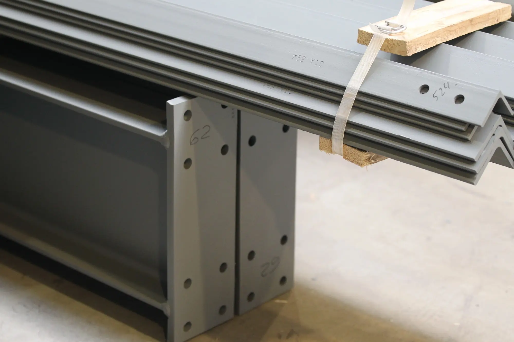 Grey powder-coated steel profiles and angles, ready for transport.