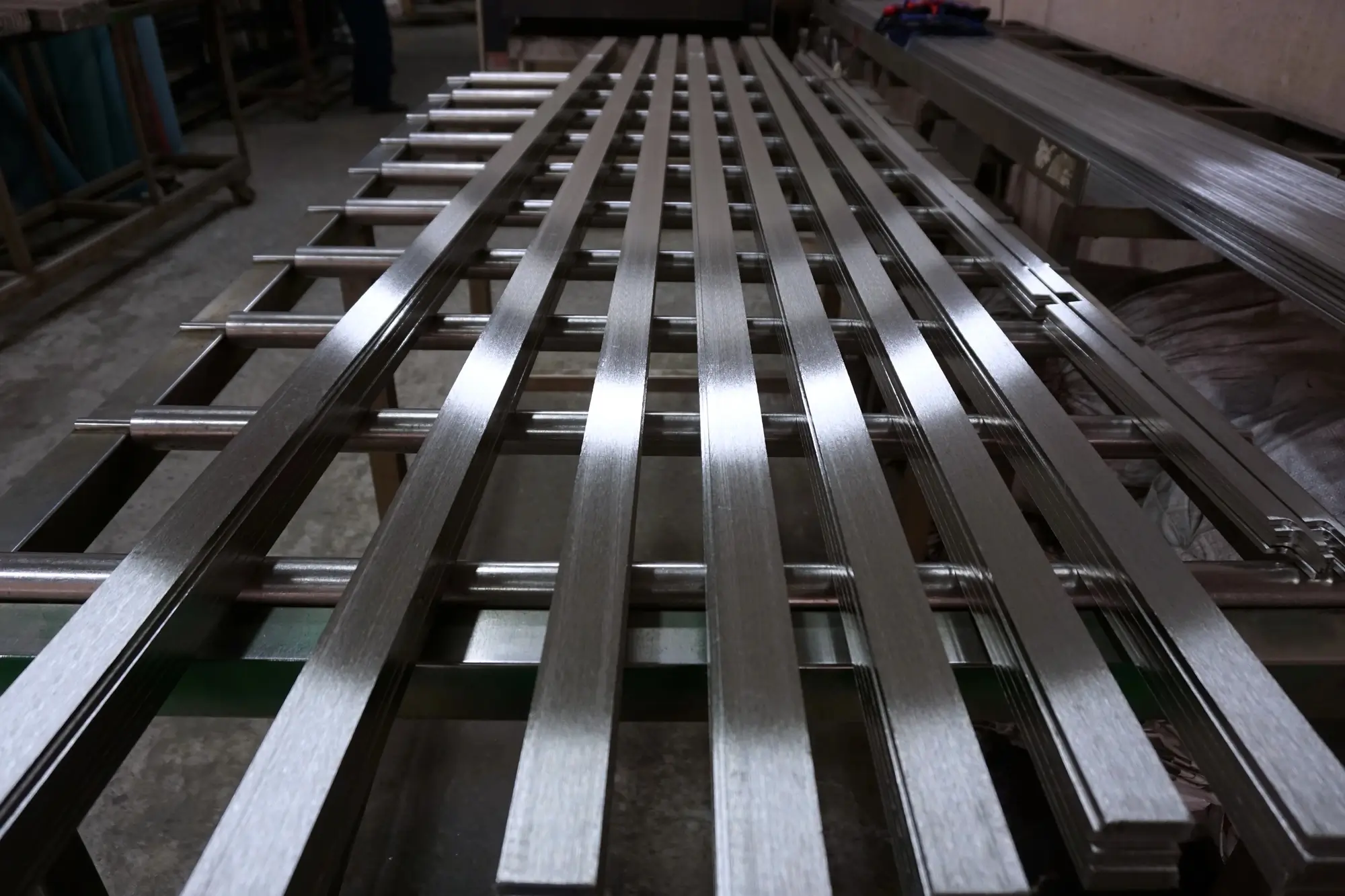 Freshly passivated, shiny metal profiles on production line rollers.